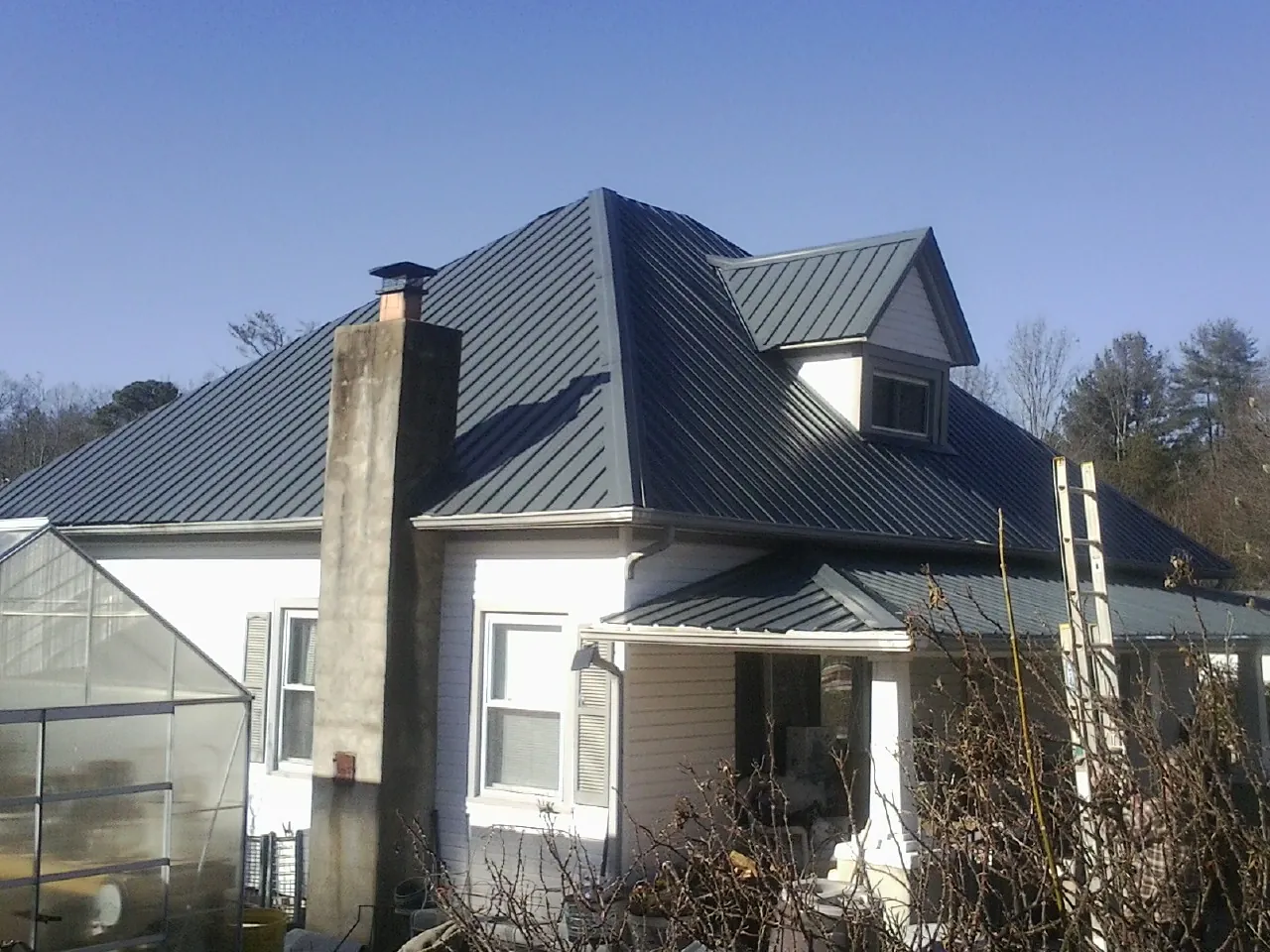 Dark blue standing seam metal roof on a white farmhouse with dormer — Slate & Tile Roof Repair by Roofing Brothers in Whippany