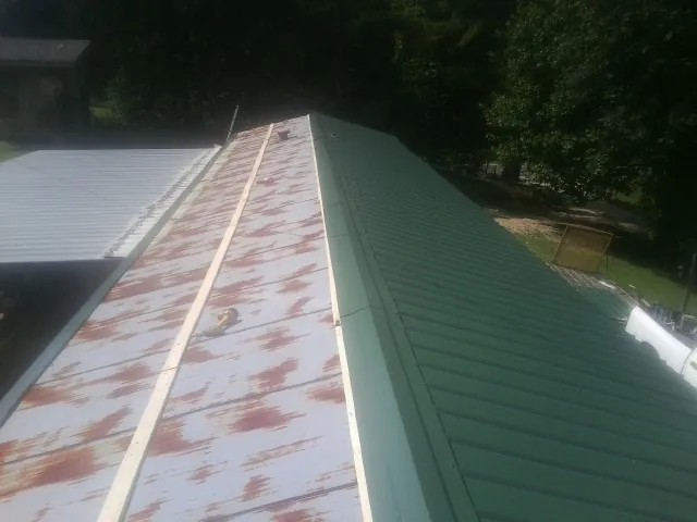 Old rusted panels beside newly installed green metal roofing — Wind Damage Roof Repair by Roofing Brothers in Whippany