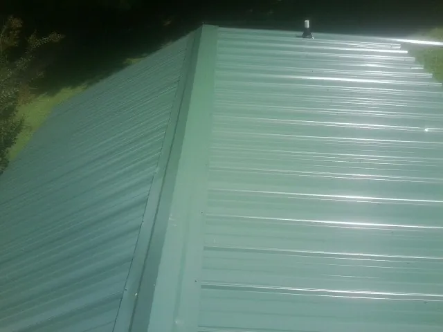 New green metal panels meeting at the ridge of a roof — Flat Roof Repair work by our crew in Whippany
