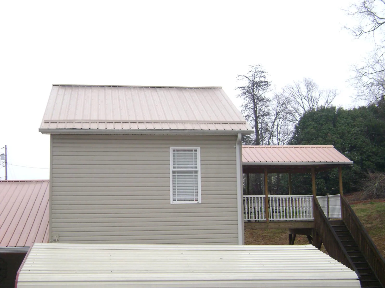 Tan metal roofs on a two story addition and attached porch, from a Roof Replacement job in Whippany