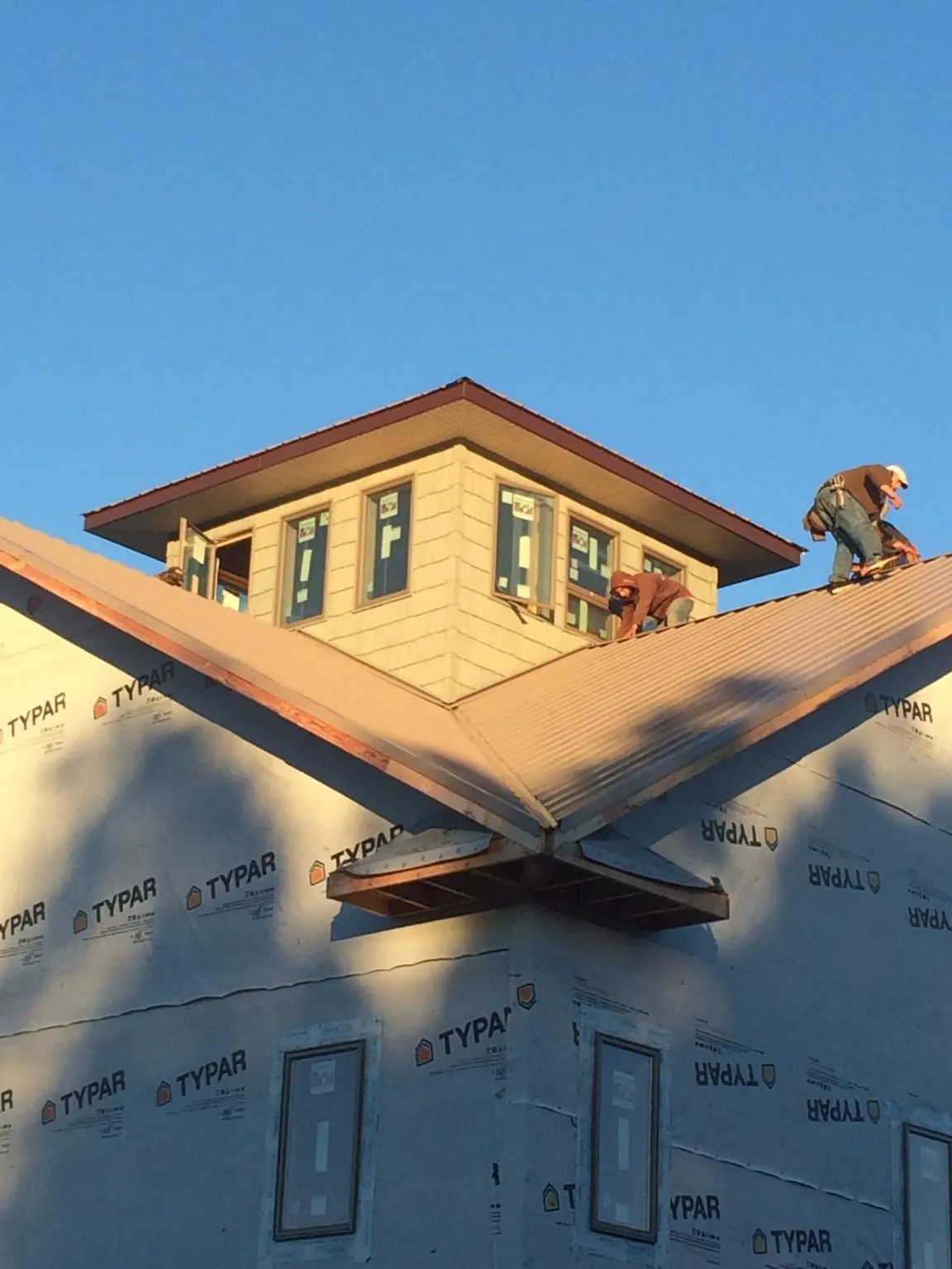 Roofers working around a rooftop cupola on a new metal roof at sunset — Roof Waterproofing in Whippany by Roofing Brothers
